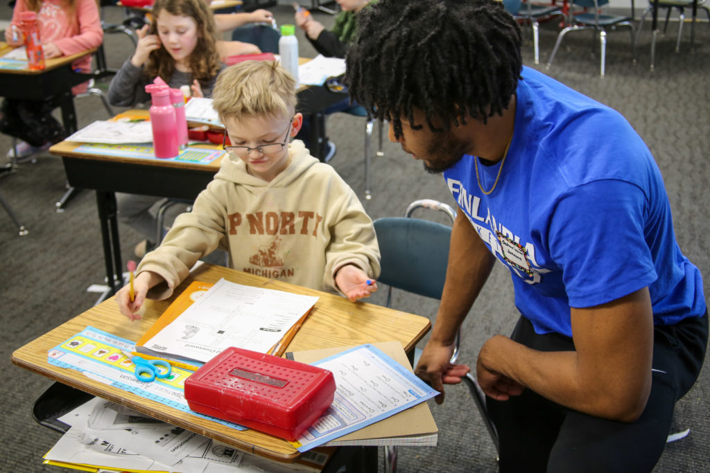 Finlandia Men's Basketball player helps Lake Linden-Hubbell Student with class work on MLK Day of Service 2023