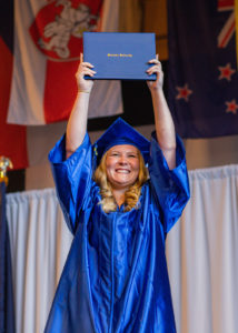Finlandia student celebrates on stage with diploma overhead at Spring 2023 Commencement